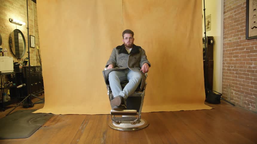 A man sits still in a chair posing for a photograph