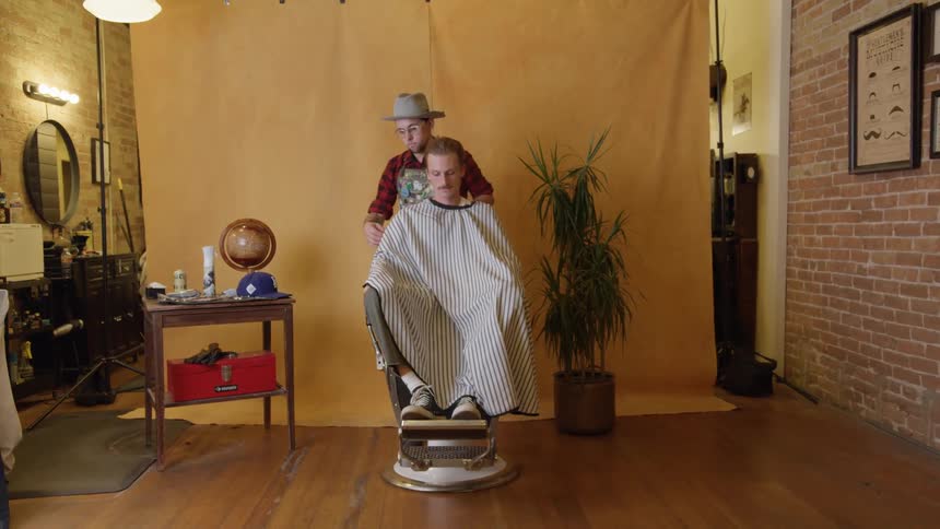 A man getting a haircut from a barber in a barbershop