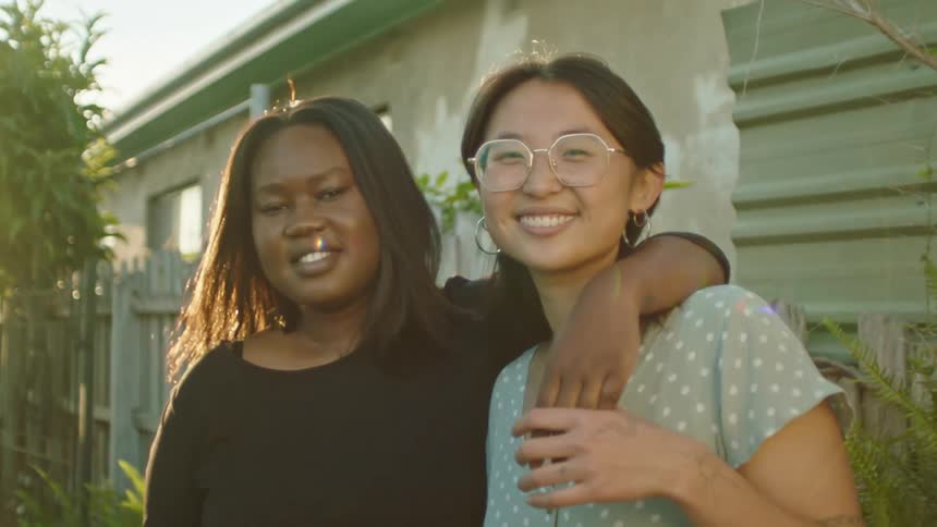 Two friends are standing outdoors and hugging