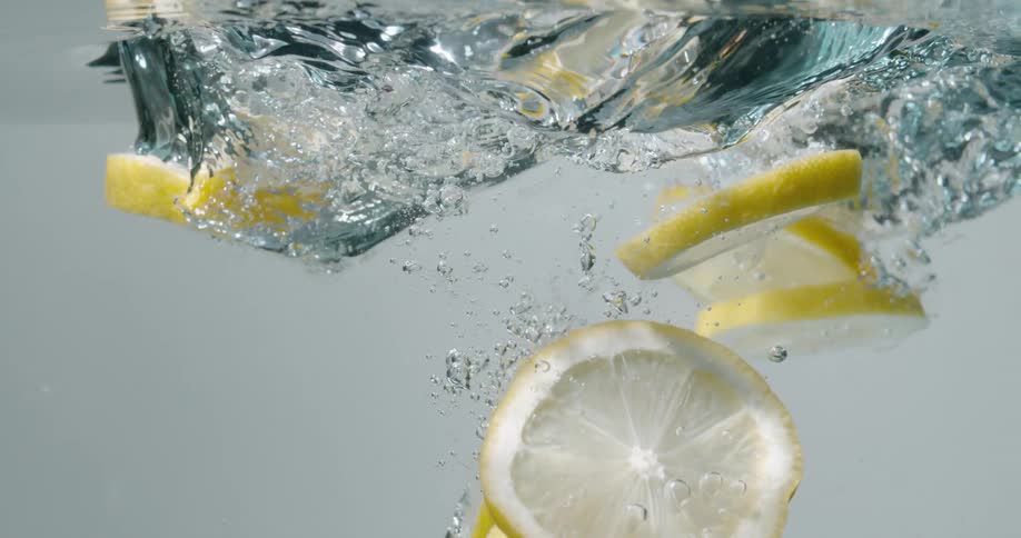 Slices of lemon being dropped in water in slow motion