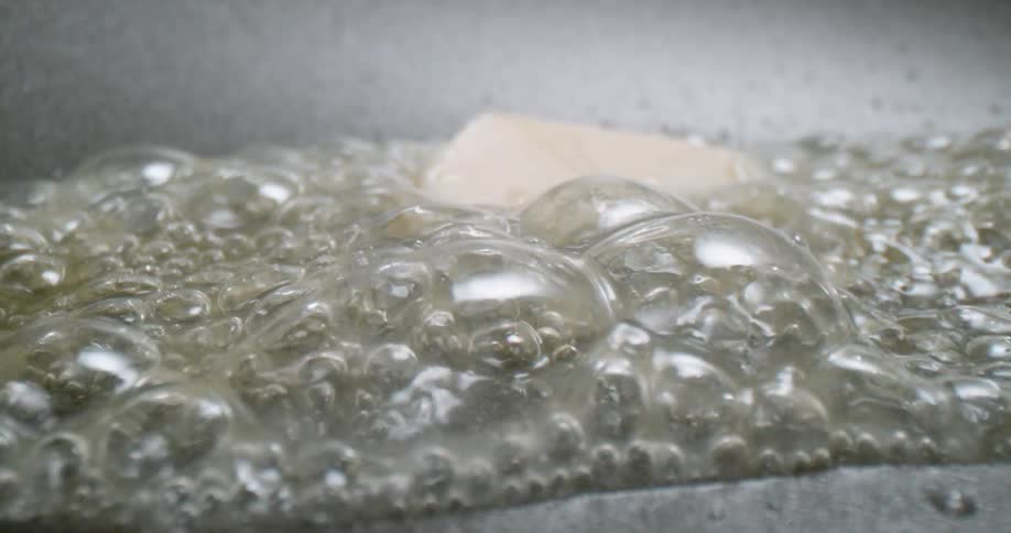 Stick of butter melting and bubbling inside a hot pan