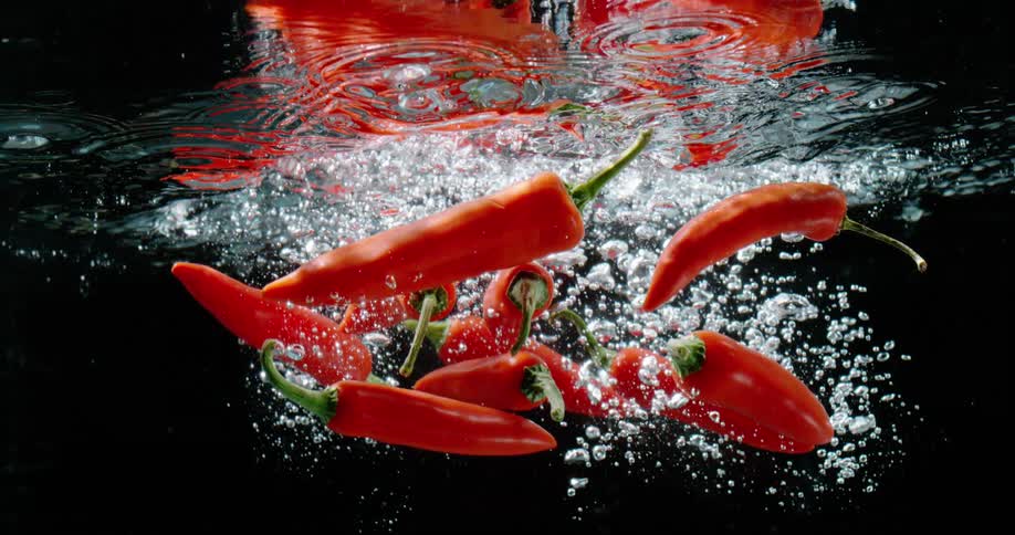 A group of peppers being thrown into water