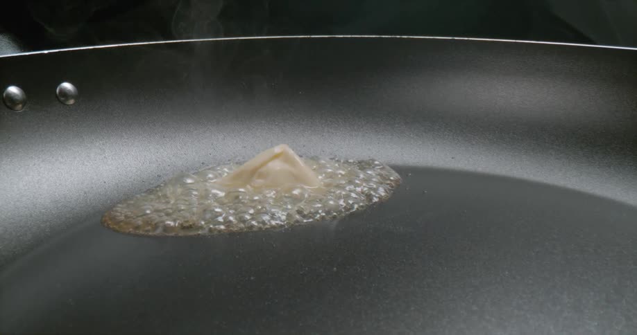Butter melting and bubbling in a frying pan with smoke