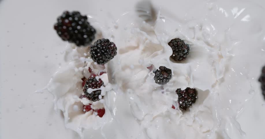 Grapes and blackberries falling into white liquid