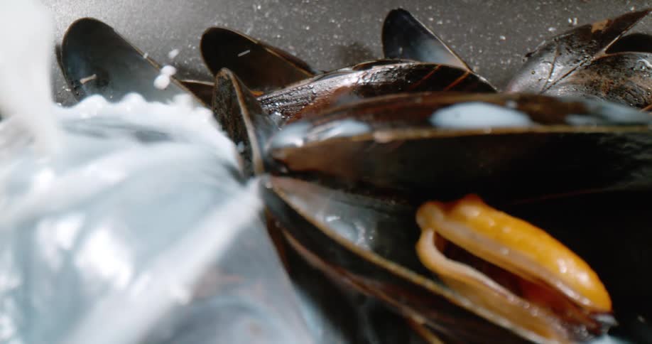 Milk being poured on clams in a bowl