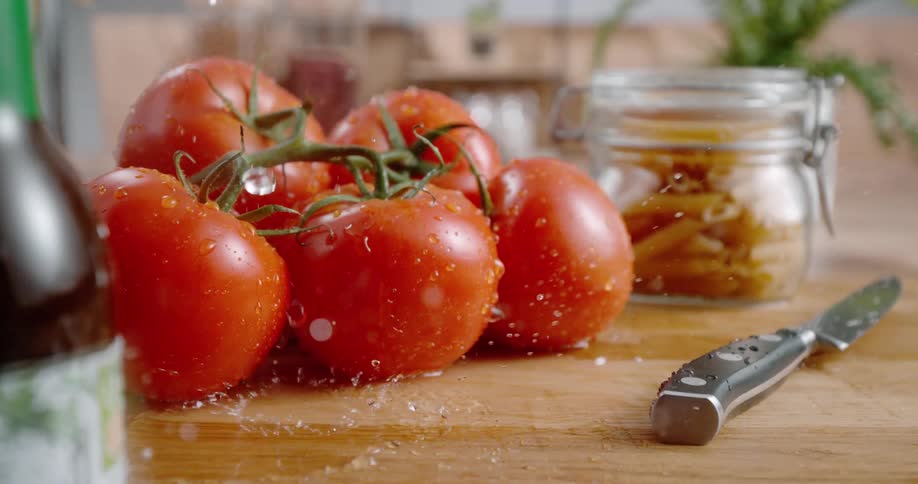 Water droplets falling on tomatoes on a cutting board with a knife