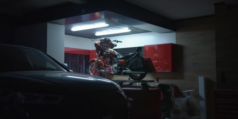 Motorcycle parked over a workbench in a garage