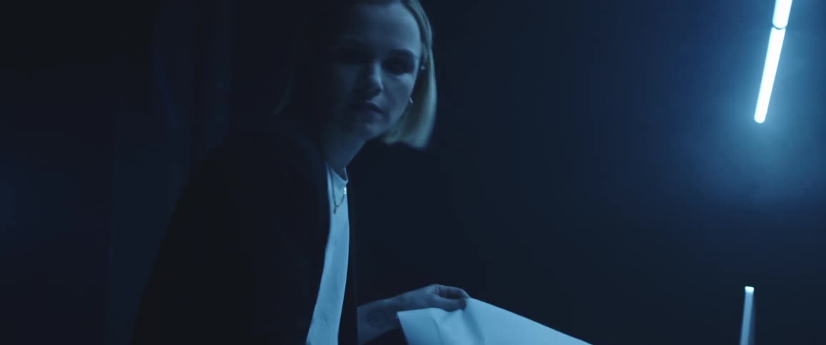 A woman focuses on her work as she picks up a piece of paper in a dark room