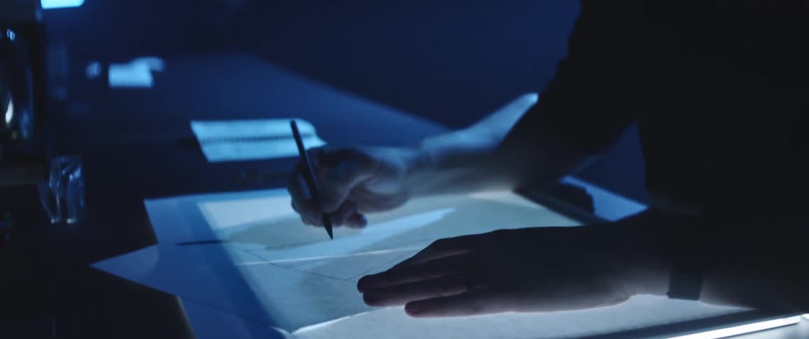 A man in an office sketches over a light box