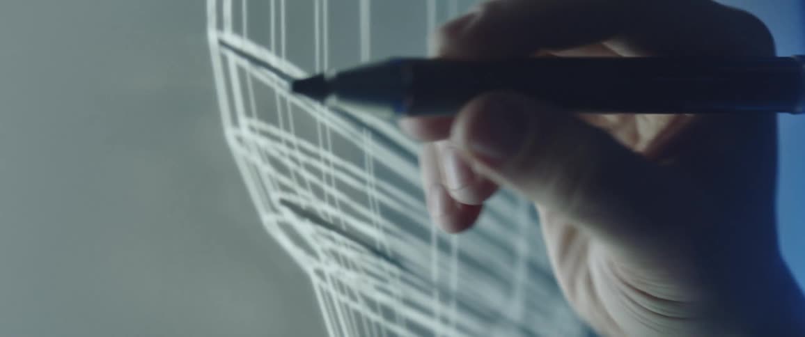 Person draws on clear surface filling in area with black pen