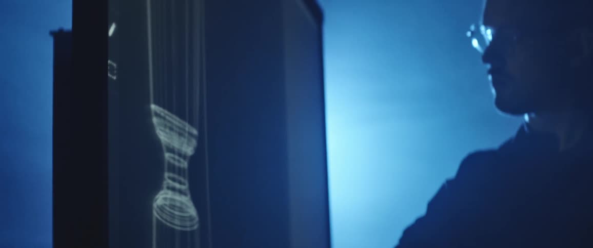 A man draws on a lit up board as a woman watches