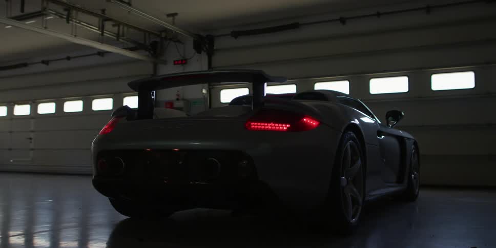 A black sports car turns on in an empty garage with multiple stalls