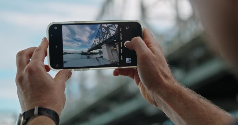 Man takes a picture of a bridge with a smartphone