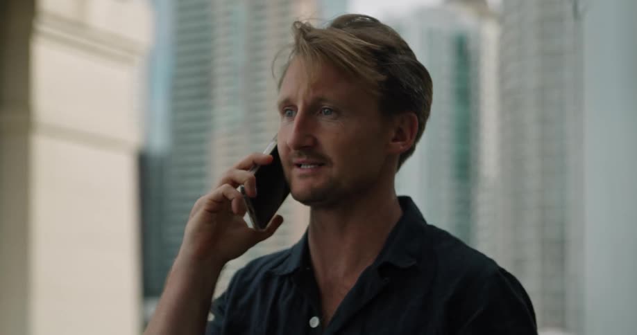 A man is standing in a room and talking on a cellphone