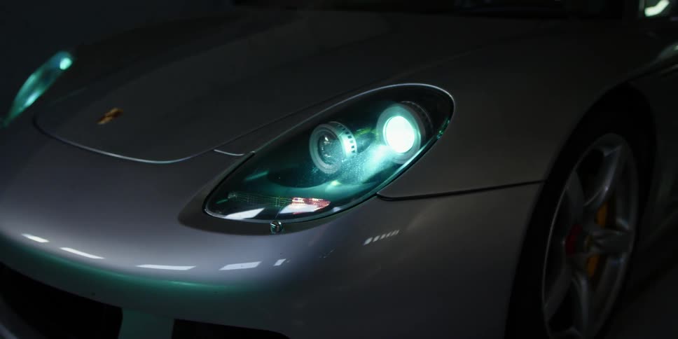 Headlights of a porsche turning on insie a dark room