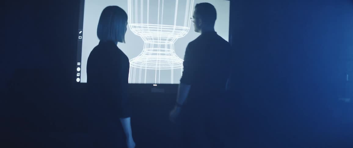 Designers working on a futuristic office review a design on an interactive screen
