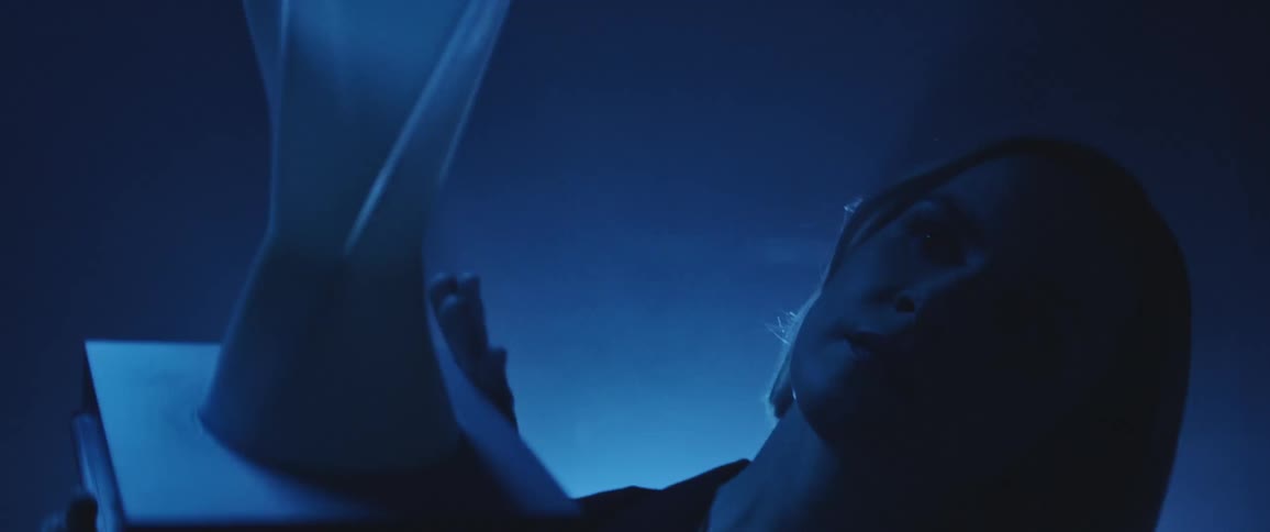 A woman examining an object in hand in darkness