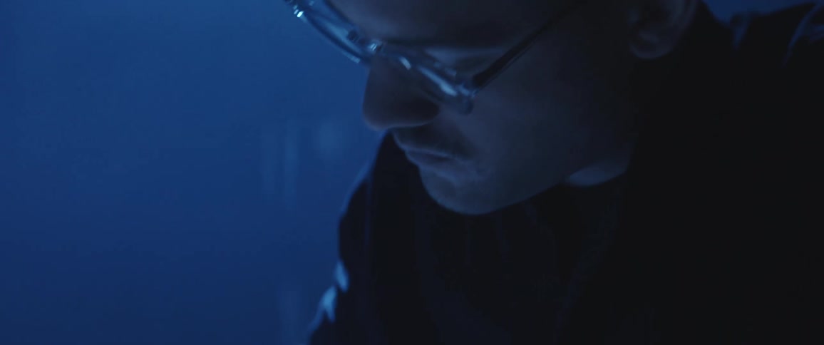Man drawing a design with pen and paper over a desk in a dimly lit office