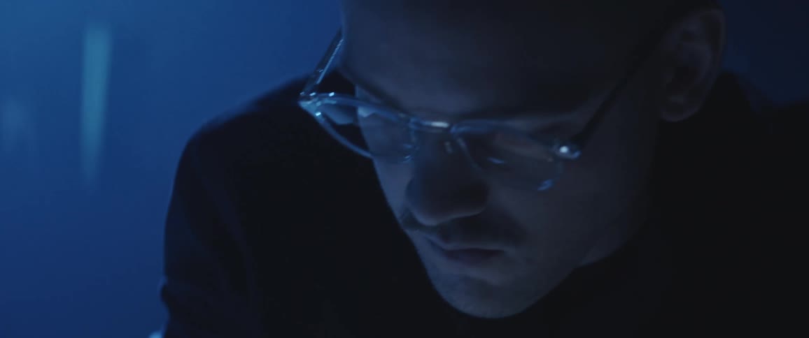 Man with glasses working on a dimly lit office