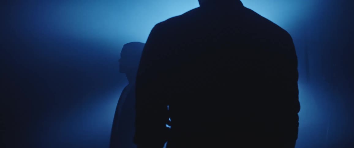 Silhouette of a man and a woman standing in front of a blue light