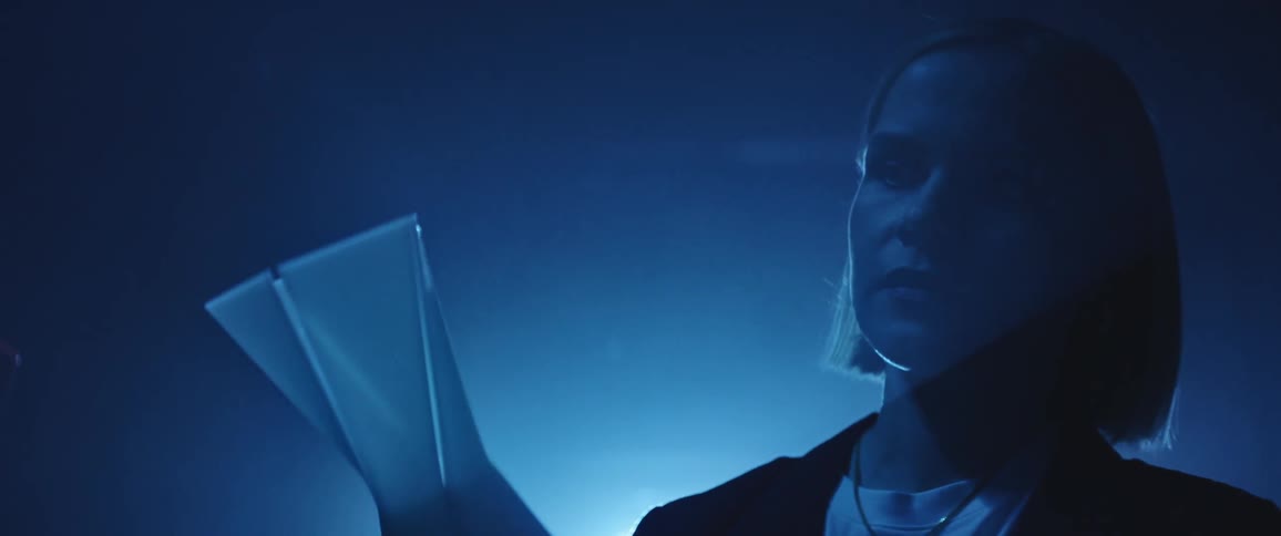 A woman in a room looking at a plastic sculpture with a light in the background