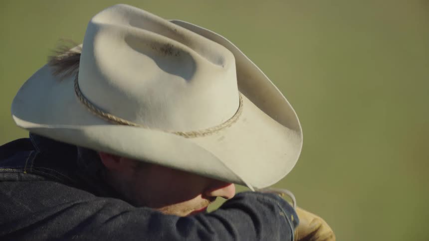 A middle aged square jaw cowboy exhales after a long days work in the far reaches of Montana on a Bison ranch