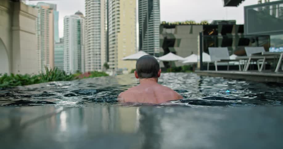 Man swimming in a pool on the terrace of a building in the city