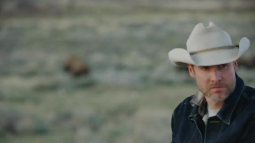 The focus changes from Bison in the background to an iconic Cowboy in the foreground