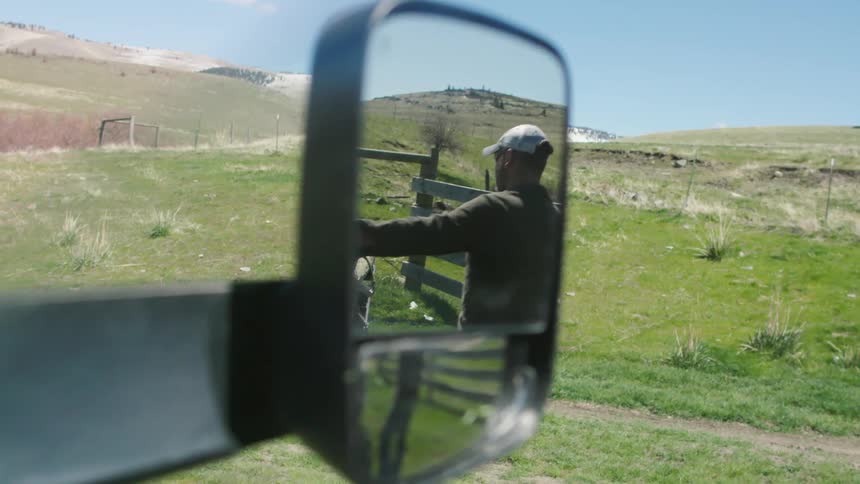 Shot of looking out the side mirror of a ranch hand preparing to unload a full pickup load of fence posts