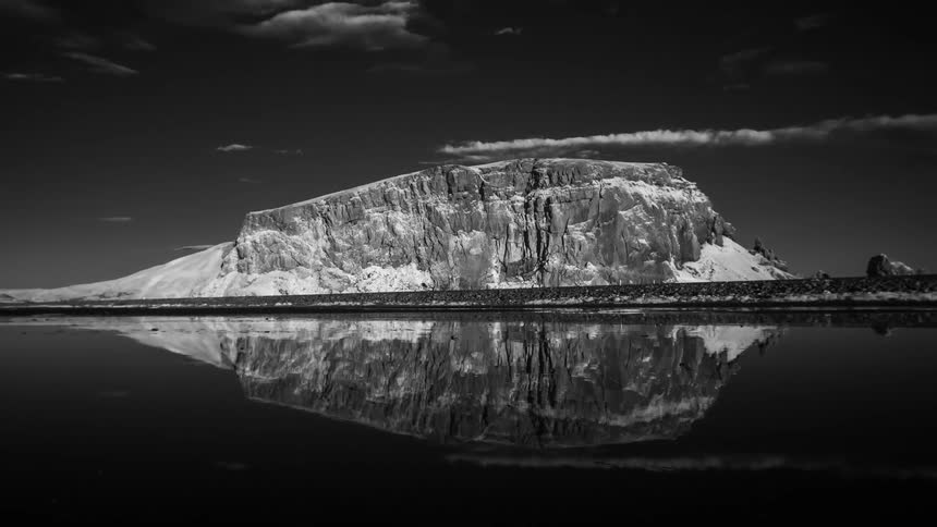 Time lapse of clouds moving over a waterway and across a mountain