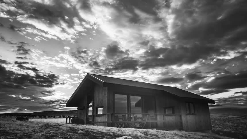 A house with a road vehicles the sky and clouds in the background