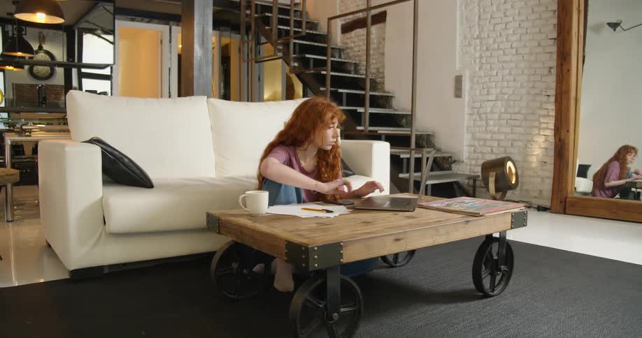 A woman typing on a laptop in a living room
