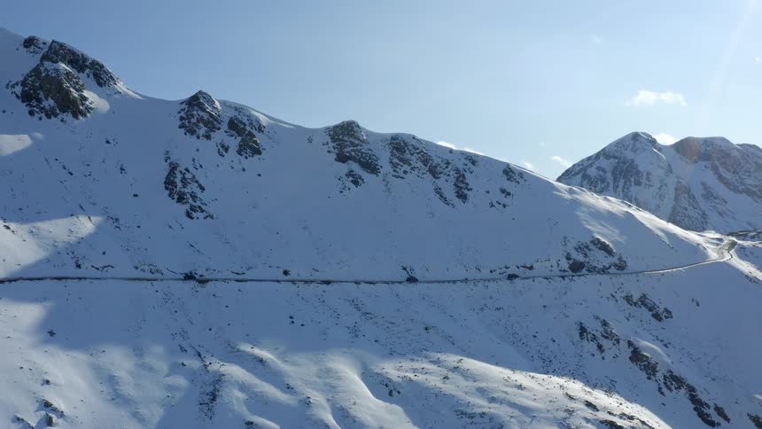 Traffic on a mountain road alongside snow covered mountains