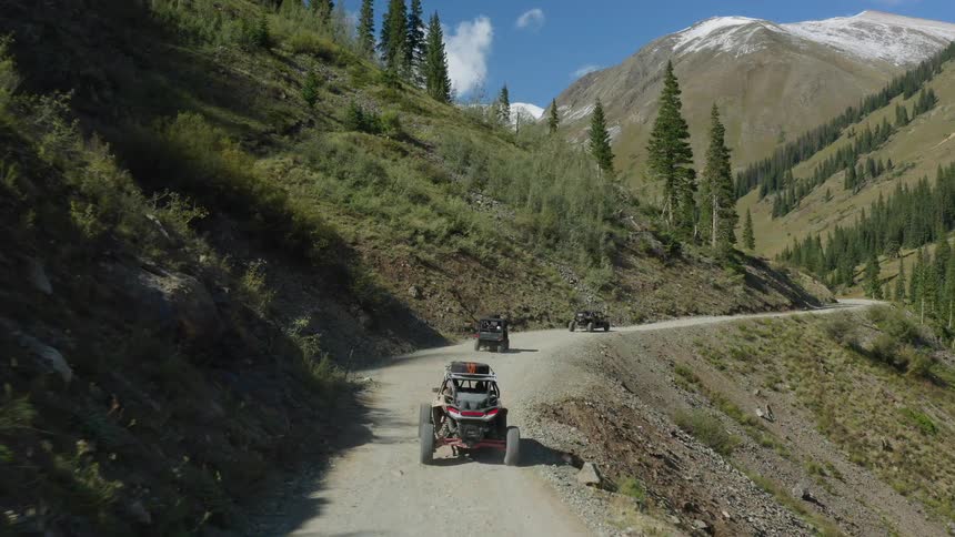 All terrain vehicles driving on a road in mountain pass through a valley