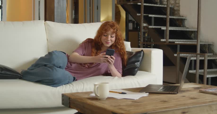 Woman reclined on the couch texting on her phone