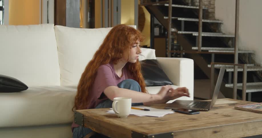 A woman using a laptop and writing on a paper