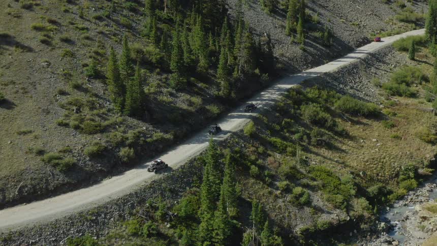 All terrain vehicles driving on a road in mountain pass through a valley