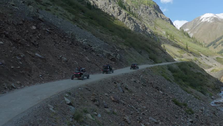 All terrain vehicles driving on a road in mountain pass through a valley