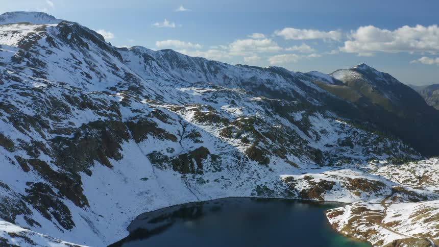 Lake surrounded by snow covered mountains under a cloudy sky