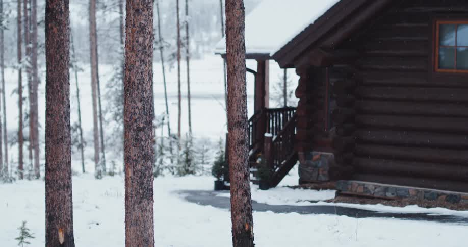 A view of a cabin in the woods on a snowy day