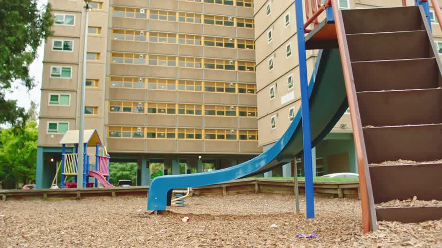 A view of a slide at a park next to a building