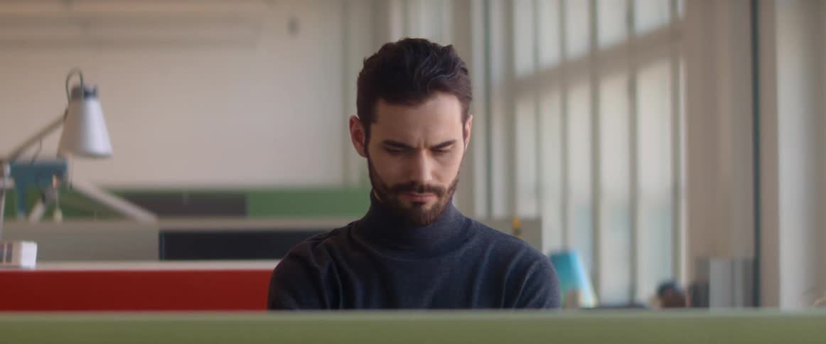 A man with a beard concentrates on his task and ponders intently while looking off to the side