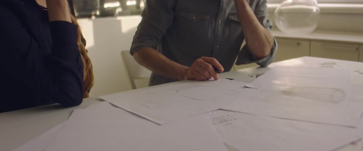 A man and woman sit at a table talking about the papers in front of them
