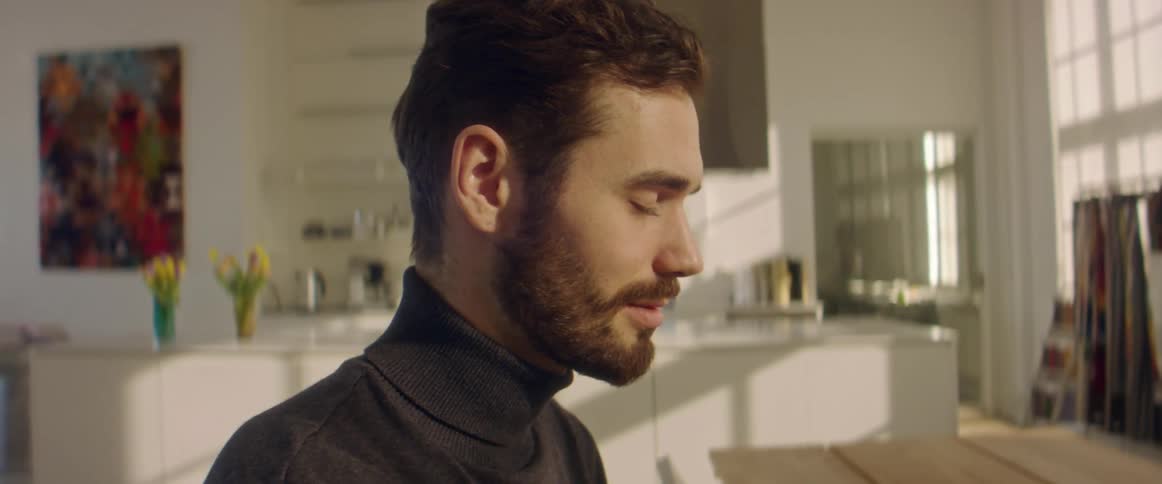A man in a room with a wall a counter and a doorway in the background