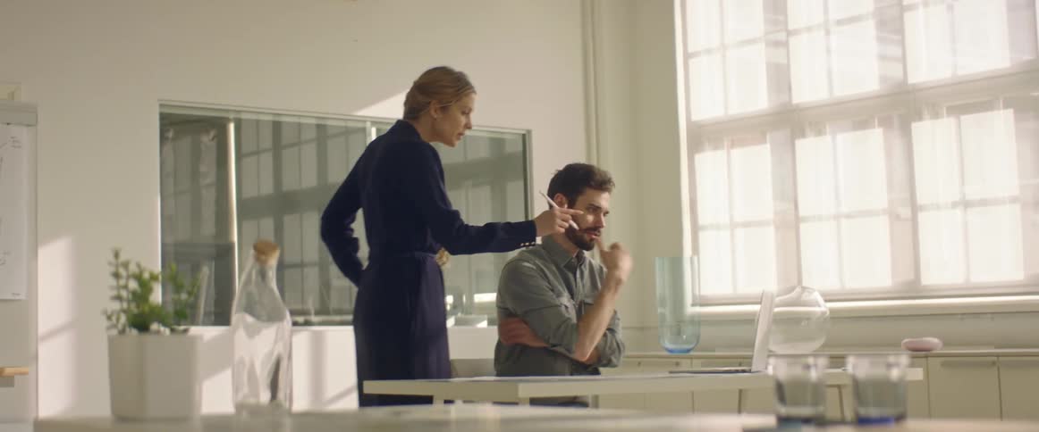 Coworkers working in an office talking in front of a laptop
