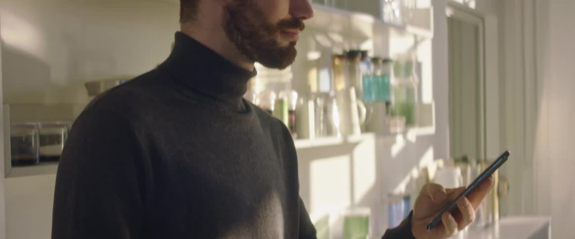 A man smiles as he uses his phone