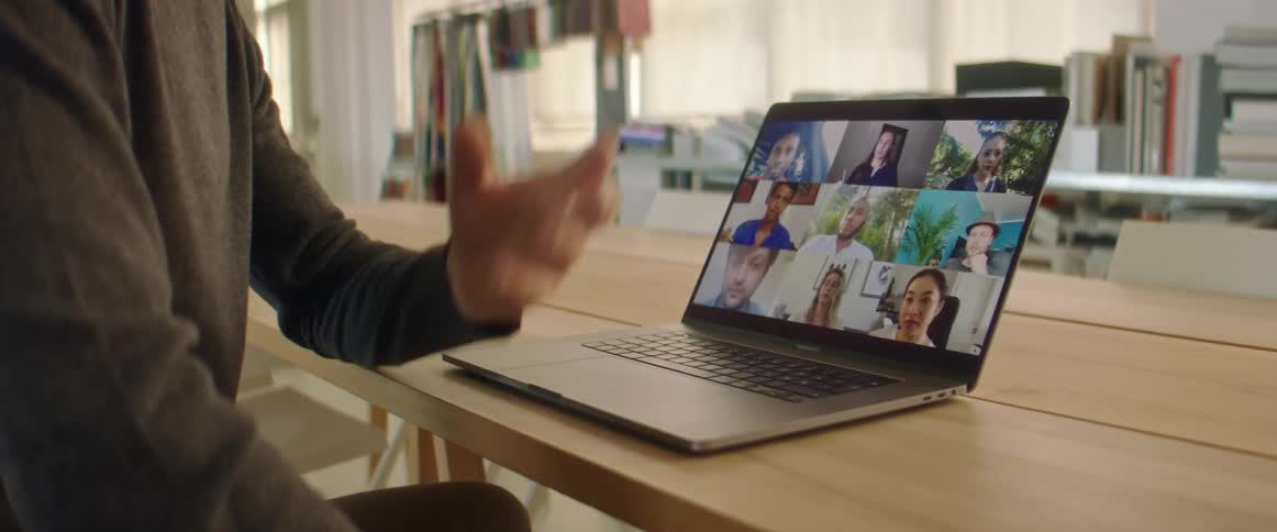 Man talking with coworkers on a video call through a laptop