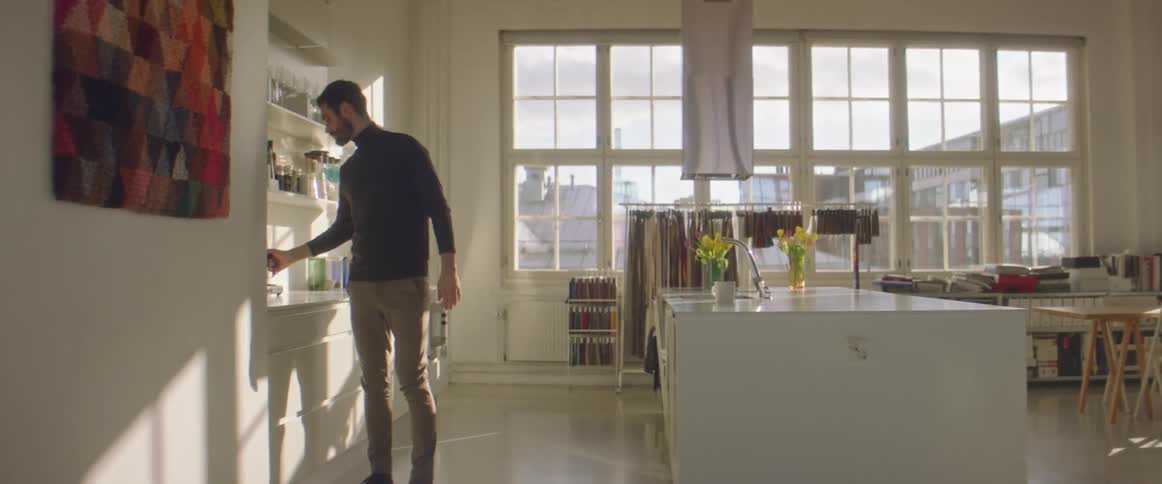 Young bearded man serving a cup of coffee in the office kitchen