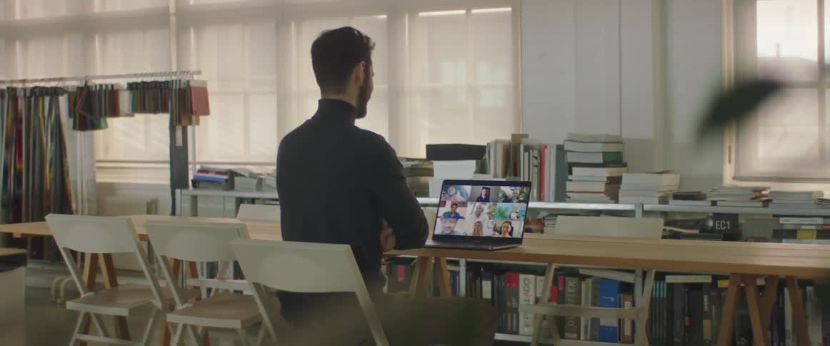 A man video chatting with a group of people on a laptop while sitting in an office
