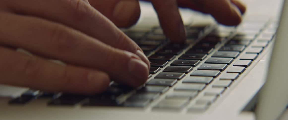 Fingers are typing on a laptop computer keyboard